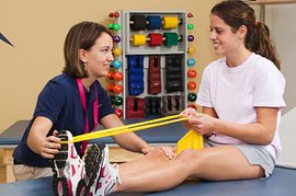 Physical therapist assisting patient with a leg band stretch